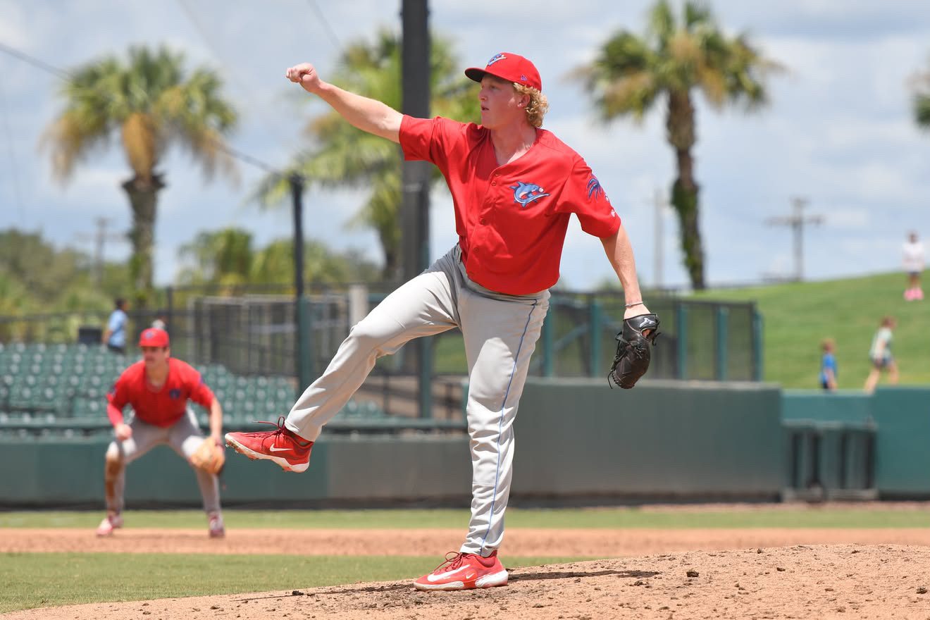 Kobe Minchey following through after a pitch in a red jersey